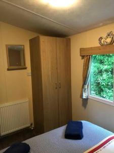 ein Schlafzimmer mit einem Bett, einem Schrank und einem Fenster in der Unterkunft Jubilee Lower Hyde Isle of Wight - Kingsgate 23 in Shanklin