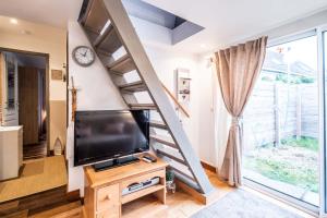 a living room with a tv and a staircase at Le gîte de Maillebois in Maillebois