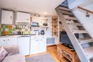 uma cozinha com armários brancos e uma escada num quarto em Le gîte de Maillebois em Maillebois