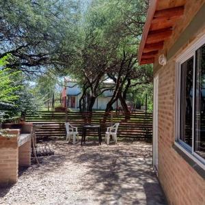 a patio with a picnic table and chairs next to a building at MONOAMBIENTES LOS SAUCES in Mina Clavero