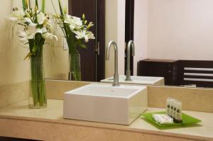 a bathroom with a sink and flowers in a mirror at Regente Palace Hotel in Buenos Aires +56 photos