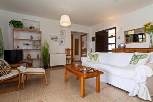 ein Wohnzimmer mit einer weißen Couch und einem Tisch in der Unterkunft Villa Mariposa in Playa Blanca