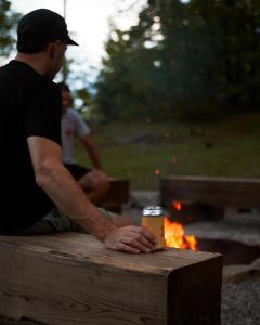 a man sitting on a bench next to a fire at Somewhere Inn Calabogie in Calabogie