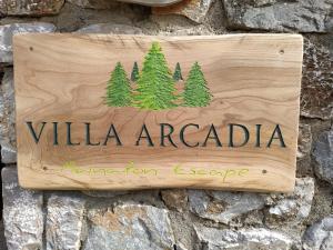 un cartello di legno su un muro di pietra di Villa Arcadia a Vlakhérna