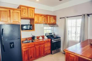 uma cozinha com armários de madeira e um frigorífico preto em La Isla Resort em Caye Caulker