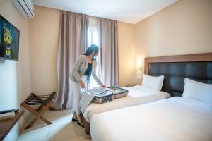 丹吉爾的住宿－北星酒店，站在酒店房间两张床旁的一位女性