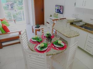 Ap (Flat) Taperapuã Porto Seguro في بورتو سيغورو: مطبخ مع طاولة عليها صحون وكاسات