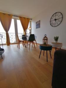 una sala de estar con mesas y sillas y un reloj en la pared en Ô Pied Marin en Le Tréport