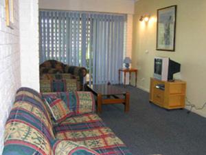 a living room with a couch and a tv at Aquarius Resort in Merimbula