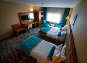 a hotel room with two beds and a desk at Capitol Hotel in Erbil