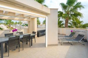 a patio with a table and chairs and palm trees at Vistabella in Orihuela Costa