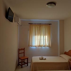 a bedroom with a bed and a window with a chair at Hospedaje Benacazon A49 in Benacazón