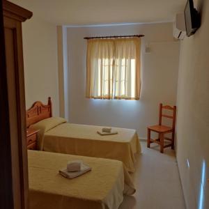 um quarto de hotel com duas camas e uma janela em Hospedaje Benacazon A49 em Benacazón