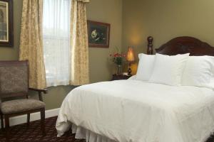 a bedroom with a white bed and a chair and a window at National Hotel Jackson in Jackson