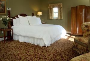 a bedroom with a large white bed and a chair at National Hotel Jackson in Jackson