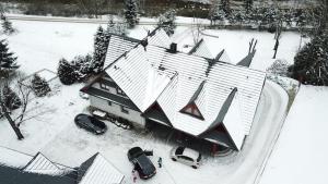 a house in the snow with cars parked in it at Apartament nad Potokiem in Witów