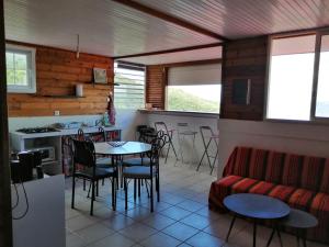 a living room with a couch and a table and chairs at Bleu topaze - vue imprenable - Les Anses d'Arlet in Les Anses-dʼArlets