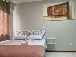 a bedroom with a bed with a painting on the wall at Ap completo, confortável e bem localizado com vaga de garagem in Joinville