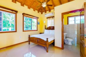 a bedroom with a bed and a toilet and windows at FLA at Hummingbird Estate Gold Standard Certified in Dangriga