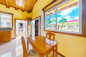 a dining room with a wooden table and windows at FLA at Hummingbird Estate Gold Standard Certified in Dangriga