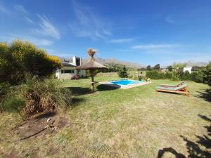 a backyard with a swimming pool and a straw umbrella at Lugar Maravilloso in Sierra de la Ventana