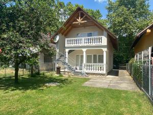 a white house with a porch and a fence at Gold Apartment in Harkány