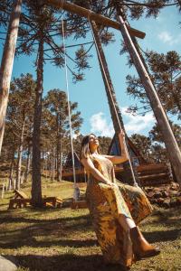 a woman in a dress sitting on a swing at URUBICI - Cabana da Montanha in Mundo Novo