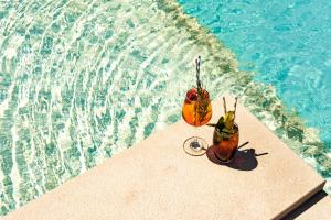 dos frutas están sentadas en el borde de una piscina en Mayflower Hotel Malta, en St Paul's Bay