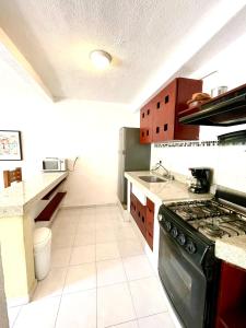 a kitchen with a stove top oven in a kitchen at Cómodo y bello departamento cerca de la Zona hotelera y el ferry a Isla mujeres in Cancún