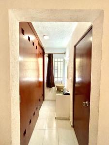 a hallway of a bathroom with a door and a sink at Cómodo y bello departamento cerca de la Zona hotelera y el ferry a Isla mujeres in Cancún