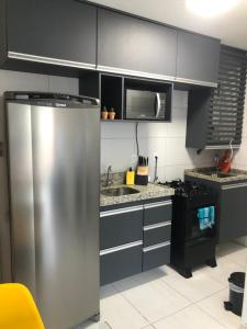eine Küche mit einem Kühlschrank aus Edelstahl und einer Mikrowelle in der Unterkunft Muro alto Condomínio Clube flat 211 in Porto De Galinhas