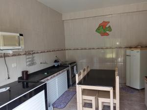 a small kitchen with a table and a microwave at Pousada Camping e Pesca Bom Abrigo in Cananéia