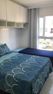 ein Schlafzimmer mit einem Bett mit einer blauen Decke und einem Fenster in der Unterkunft Muro alto Condomínio Clube flat 211 in Porto De Galinhas
