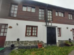 Casa blanca con puerta y ventanas negras en Departamentos Ahnen en Ushuaia