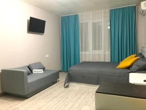 PashkovskiyにあるApartments on Sormovskayaのベッドルーム1室(ベッド1台、ソファ、青いカーテン付)
