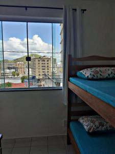 a bedroom with a view of a city from a window at Hostel Alto do Rosario in Vitória