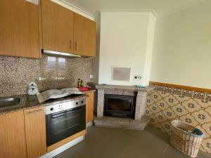 La cocina está equipada con fogones, fregadero y horno. en casa das Termas do Carvalhal en Carvalhal