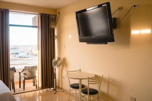 a living room with a table and a tv on the wall at Hotel Marina Del Bay in Paita