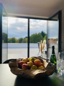 un cuenco de madera de manzanas en una mesa con una botella de vino en Ferienwohnungen Nalbach Bierbach, en Nalbach