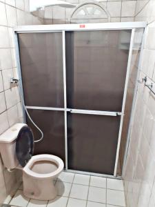 a bathroom with a toilet with a sliding glass door at Hostel Alto do Rosario in Vitória