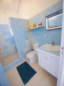 a blue tiled bathroom with a toilet and a sink at 2 Bedroom Apt with Breathtaking view in Oyster Pond