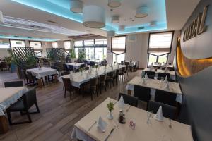 un restaurante con mesas y sillas blancas y ventanas en Hotel Crystal en Pećinci