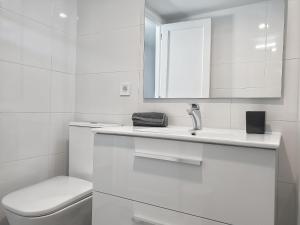 a white bathroom with a toilet and a sink at Tamaran 106 Vv Maspalomas in Playa del Ingles +16 photos