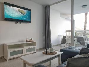 a living room with a couch and a tv on a wall at Tamaran 106 Vv Maspalomas in Playa del Ingles