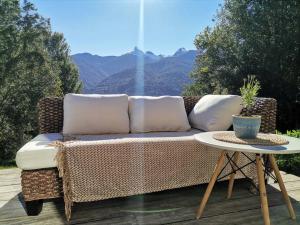 a wicker couch sitting on a deck with a table at Acogedora cabaña en el bosque, acceso solo vehiculos 4x4 in Cochamó