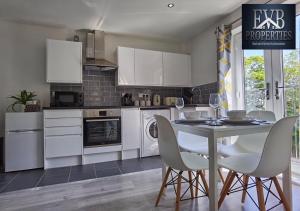 een keuken met witte kasten en een tafel en stoelen bij Spireview 2 Bedroom Apartment EVB Properties Short Lets & Serviced Accommodation ,Titanic City- Southampton in Southampton