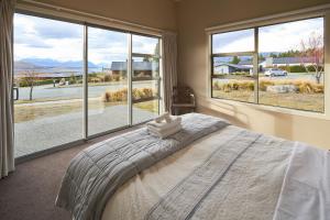 a bedroom with a bed and large windows at Lake Watch - Lake Tekapo in Lake Tekapo