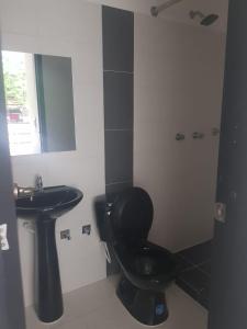 ein Bad mit einem schwarzen WC und einem Waschbecken in der Unterkunft Apartaestudio Colibrí in Buga
