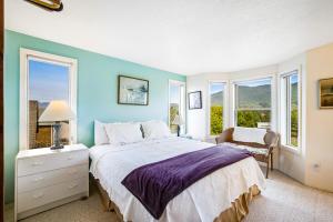 a bedroom with a large bed with blue walls and windows at Seabird Lodge in Rockaway Beach