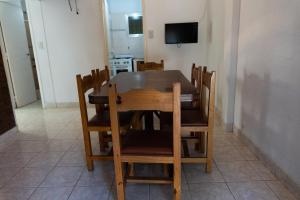 una mesa de madera y sillas en una habitación con TV en Alfil Apartamentos Villa Gesell, en Villa Gesell
